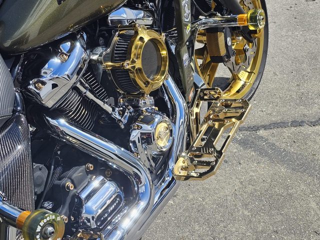 Motor und Vorderrad aus der Nähe, Chrom und goldene Felge spiegeln das Licht